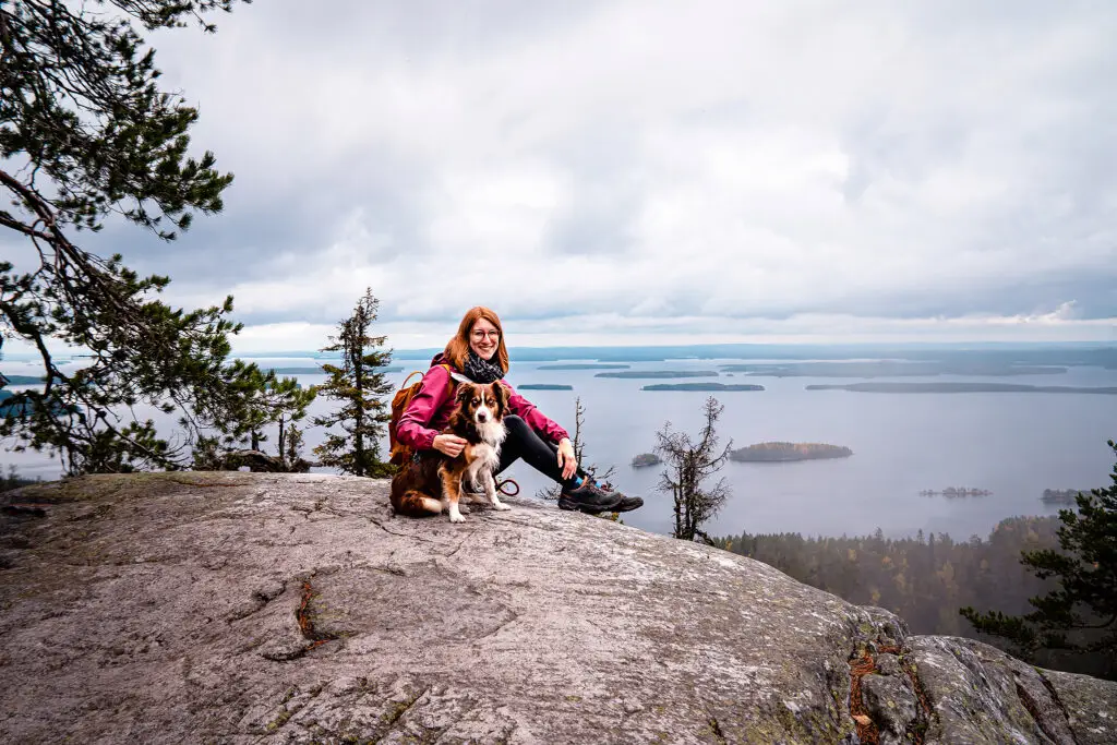 Frau mit Hund auf einem Felsen auf dem Berg Koli in Finnland